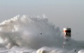 Big wave against beacon and pier in the north of Portugal in a stormy morning - mouth of river Douro, Porto
